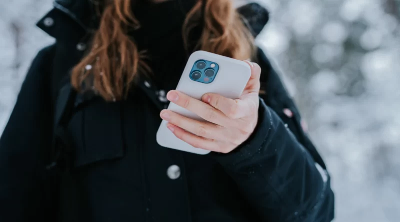 kobieta w kurtce zimowej z iphone w dłoni